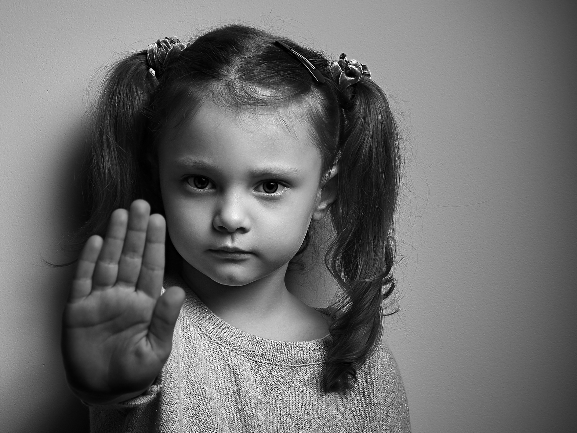 Flicka i svartvitt format som sträcker ut handen som en symbol för stopp. 