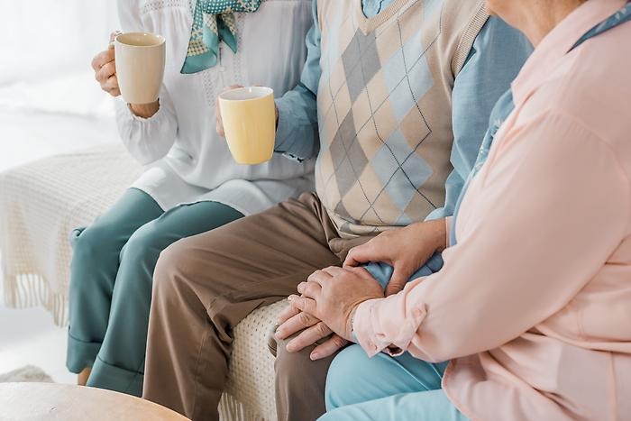 På bilden syns tre stycken äldre människor som sitter med varsin kopp kaffe i handen. 