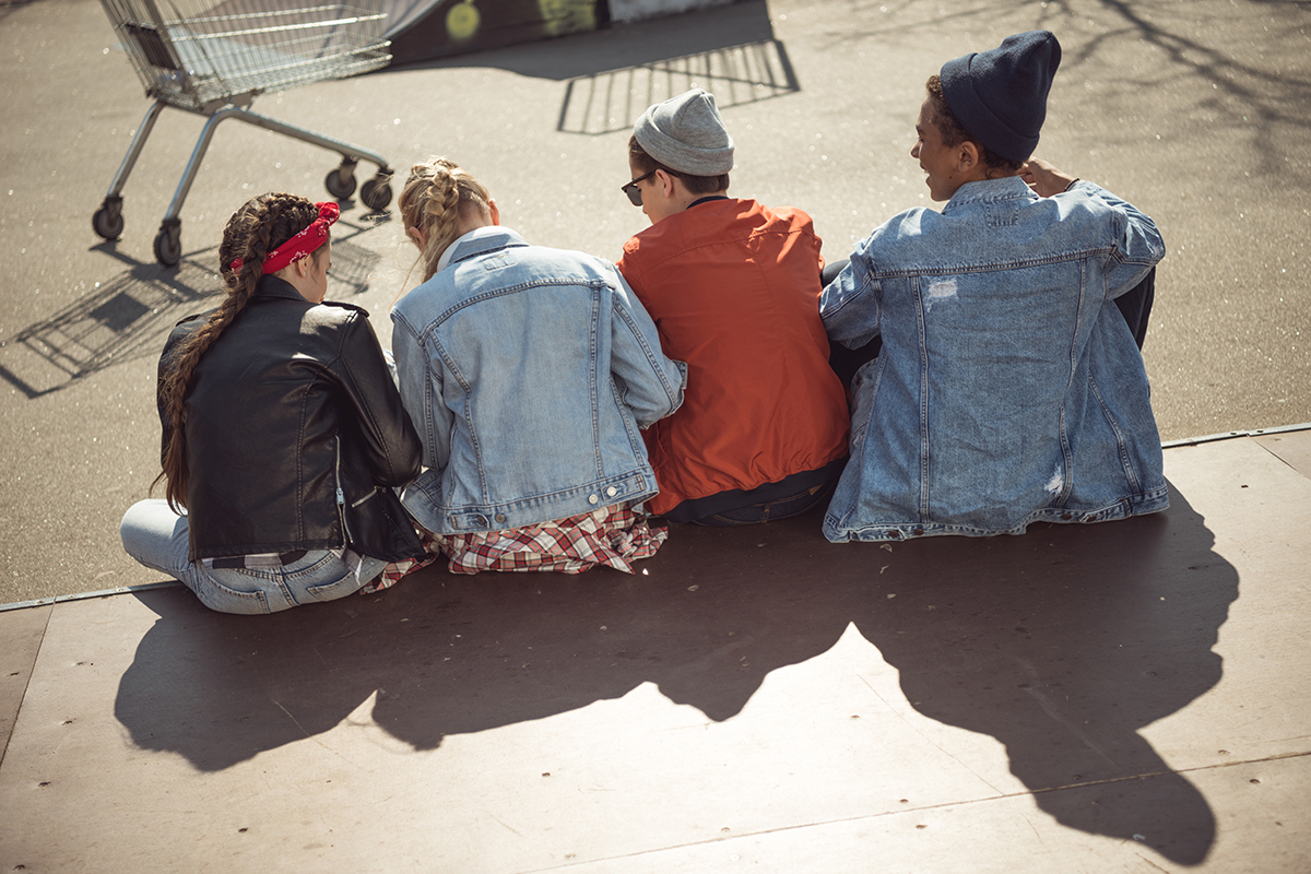 Fyra ungdomar sitter och pratar ute.