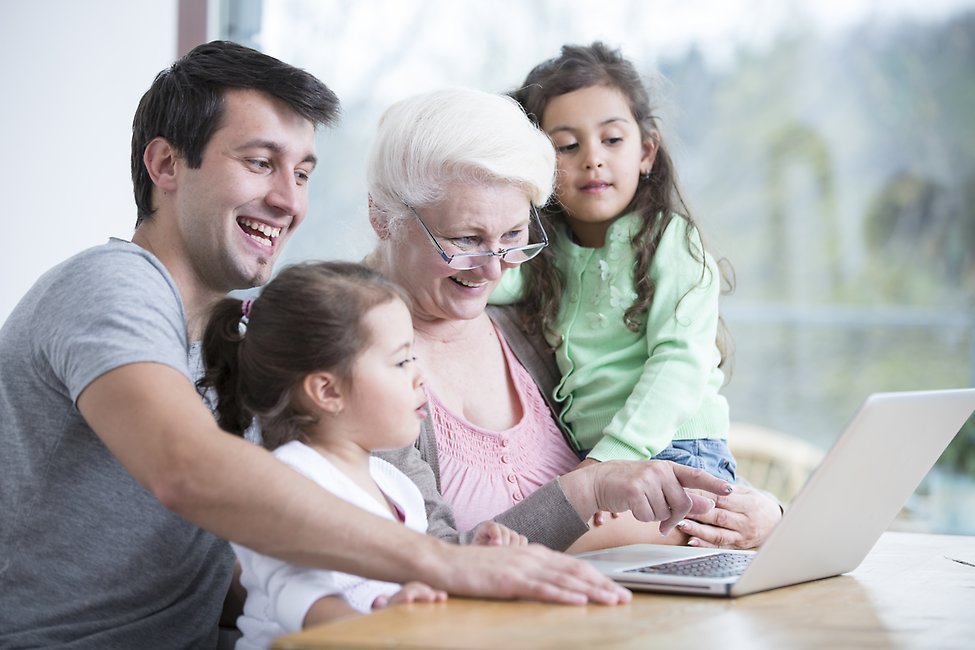 En ung man, två barn och en äldre kvinna som tillsammans sitter vid en dator.