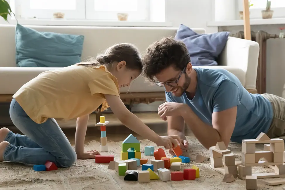 Bild på en pappa och dotter som leker med färgglada klossar. 